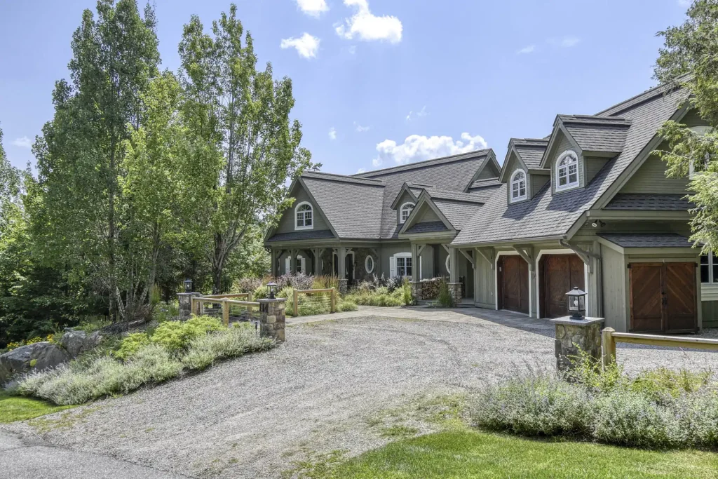 Grande maison à pignons avec garage, allée gravillonnée et arbres environnants
